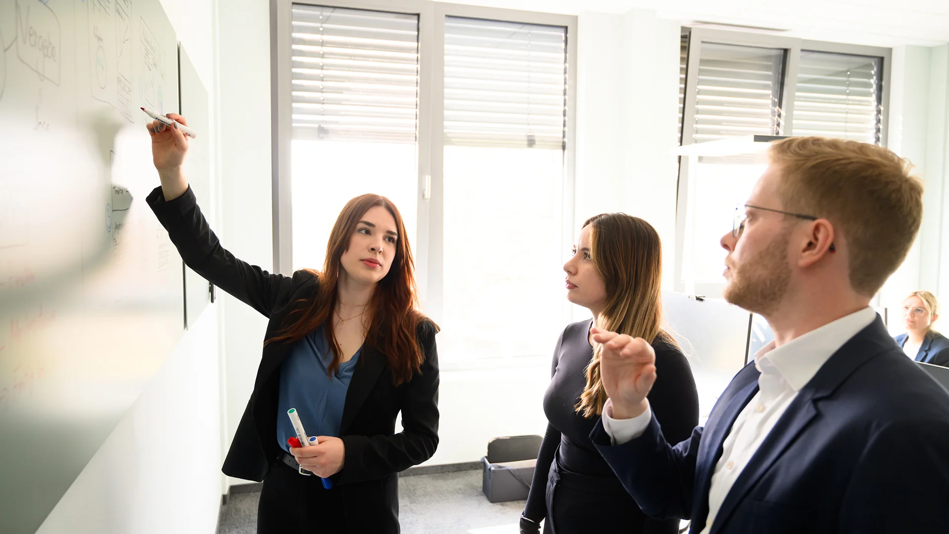 Mitarbeitende von ai Consult entwickeln gemeinsam Ideen an einem Whiteboard in einem modernen Besprechungsraum – steht für Teamarbeit, Kommunikation und interdisziplinäre Zusammenarbeit im Ingenieurbüro.