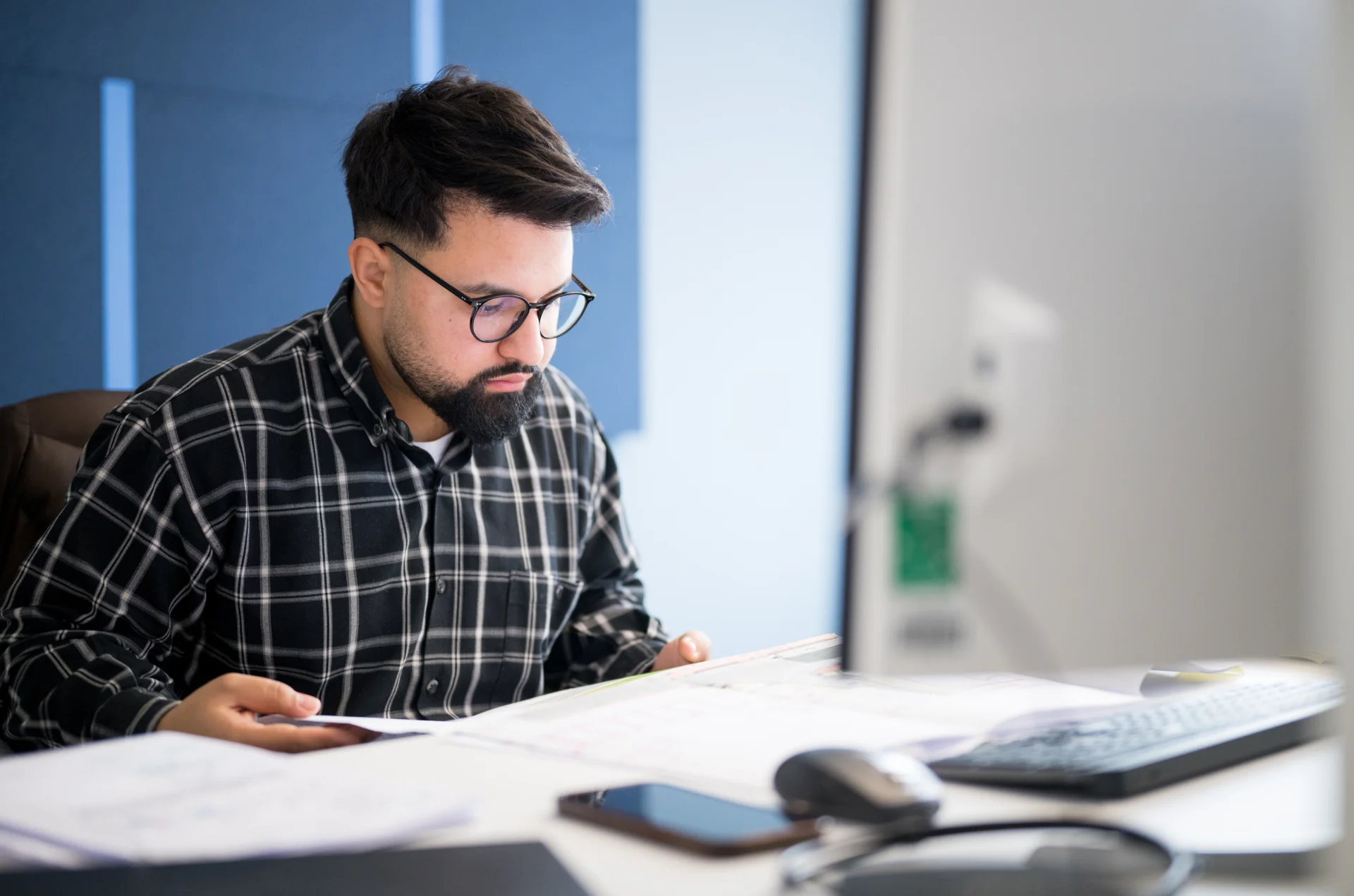 Mitarbeiter von ai Consult arbeitet konzentriert an technischen Plänen am Schreibtisch – steht für digitale Planung, Präzision und innovative Ingenieurarbeit mit BIM-Technologie.