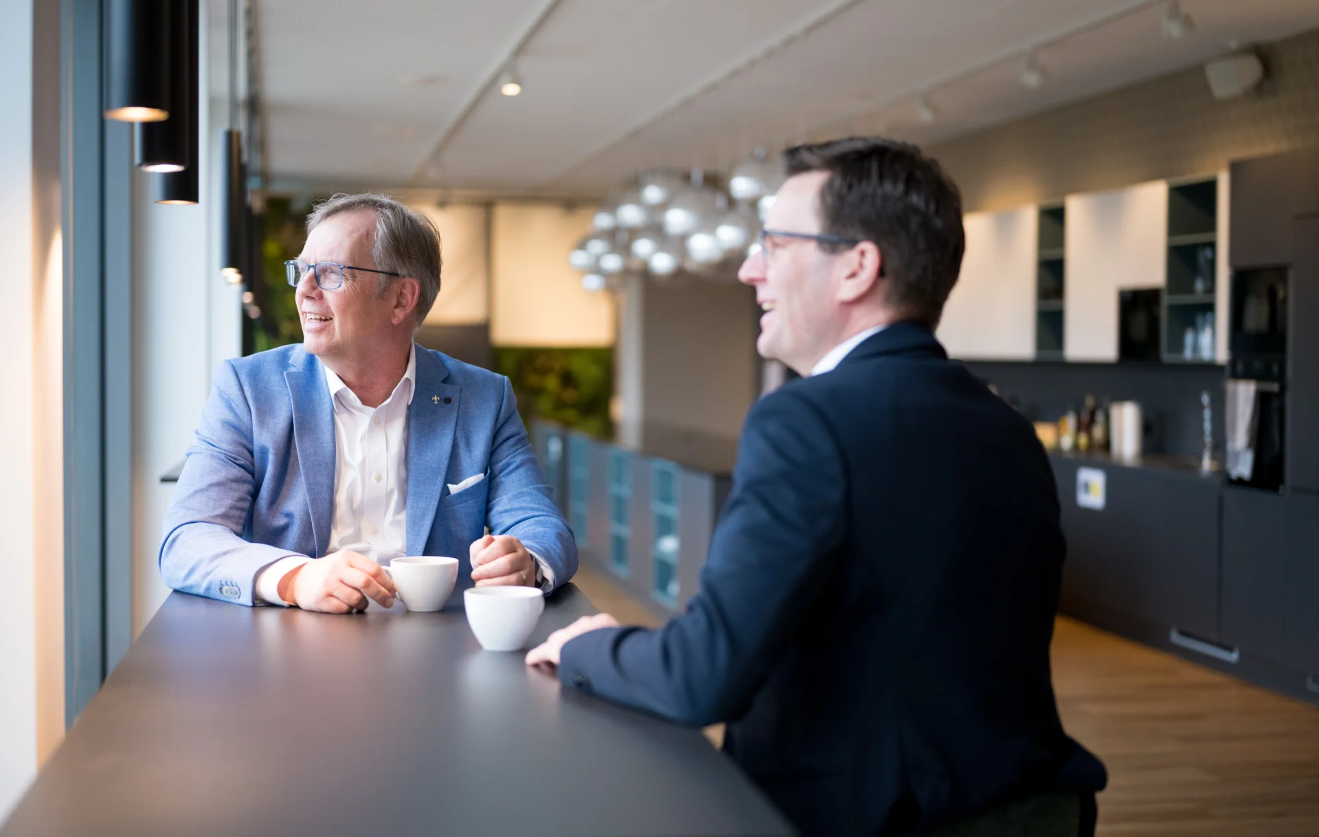 Marc Hackmann und Sebastian Dopp, Geschäftsführer der ai Consult GmbH, im Gespräch bei einer Kaffeepause im Büro – steht für Vertrauen, Führung auf Augenhöhe und die offene Unternehmenskultur des Unternehmens.